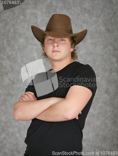 Image of Beautiful serious young man in cowboy hat on grey background