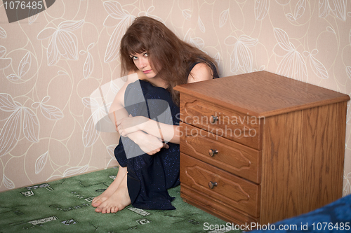 Image of Beautiful sad girl in a dress sits in a corner