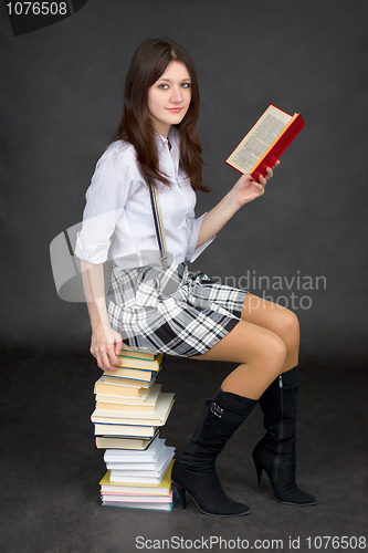 Image of Beautiful young woman reads on a pile of books on black backgrou