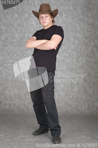 Image of Young guy in cowboy hat standing on a grey background