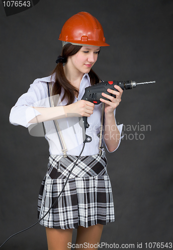 Image of Girl in helmet standing on a black background with drill