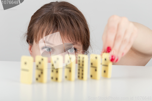 Image of Girl builds line of dominoes counters close up