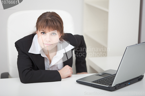 Image of Resolutely woman - managing director sits at table with laptop