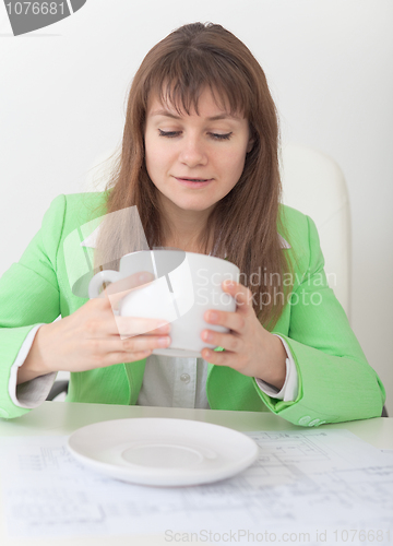 Image of Woman looks in huge cup for coffee
