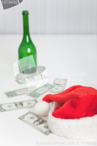 Image of On white table bottle, christmas hat and money