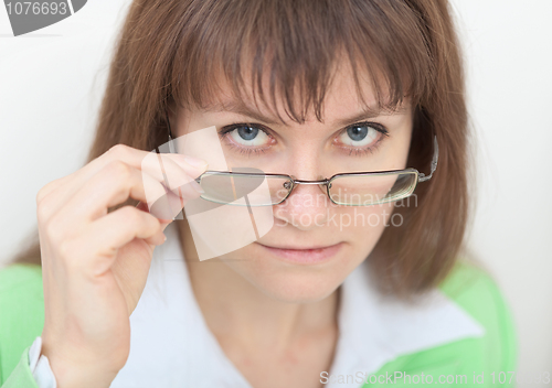 Image of Strict young woman looks at us over eyeglasses