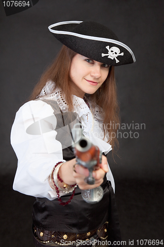 Image of Young woman in suit of the pirate aims a pistol