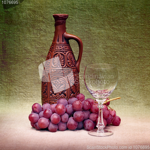 Image of Still-life with clay bottle, glass and grapes against canvas