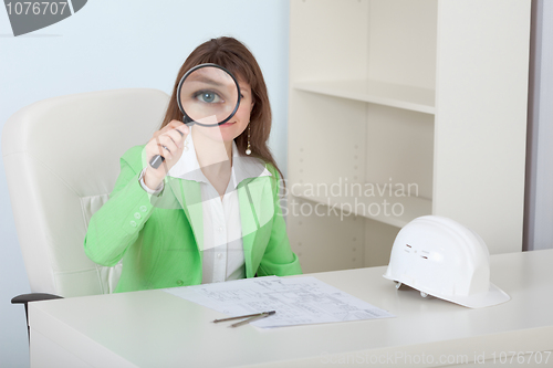 Image of Woman engineer looks at us through magnifier with smile