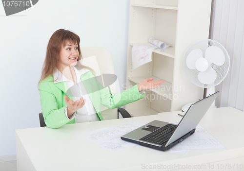 Image of Emotional girl rejoices sitting in office with laptop