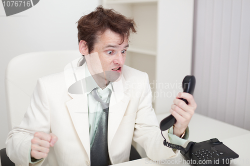 Image of Person emotionally communicates with phone at office