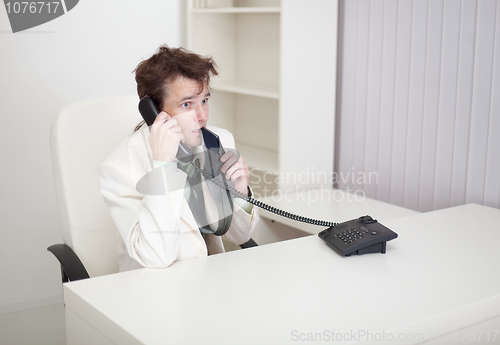 Image of Businessman speaks on phone, worries and eats tie