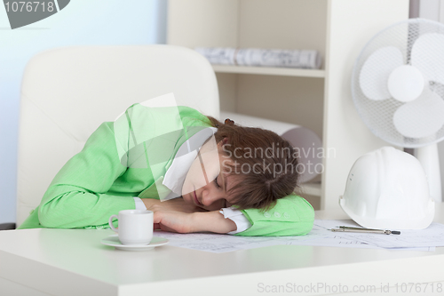 Image of Girl sleeps on table at office in working hours