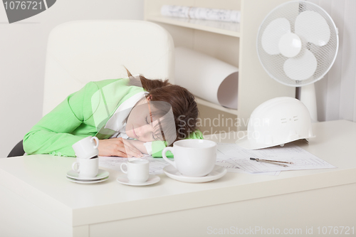 Image of Businesswoman  sleeps sitting at table on workplace