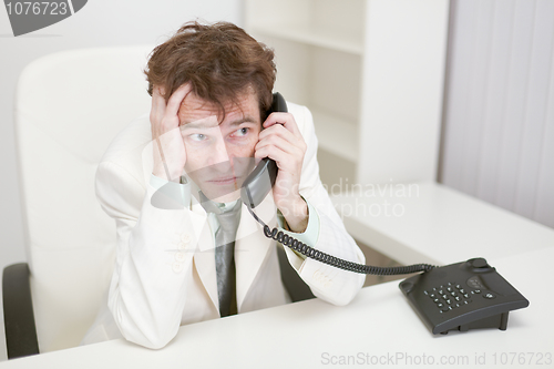 Image of Frightened guy speaks by phone at office