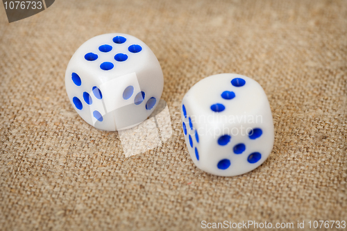 Image of Two playing dices with blue points on brown canvas