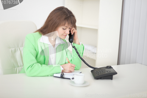 Image of Secretary speaks on the phone doing records in notebook