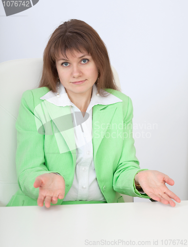 Image of Woman sitting at table with astonishment makes helpless gesture