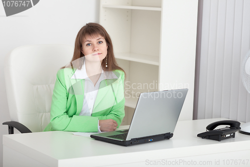 Image of Beautiful young girl - manager sits at a table in office