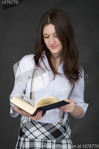 Image of Beautiful young woman reads big book on black background