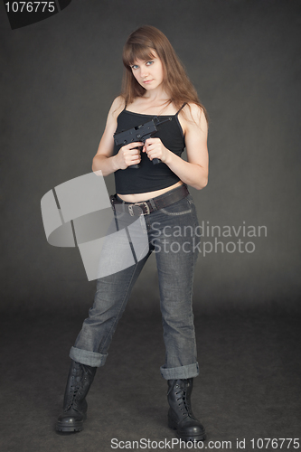 Image of Young girl in jeans with an automatic pistol in hands