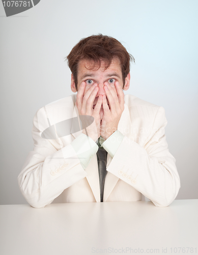 Image of Young sorrowful people in white suit sits at table