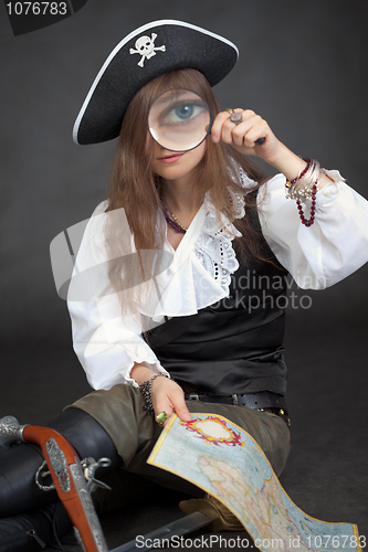 Image of Woman in clothes of pirate with sea map and magnifier glass