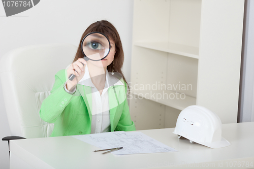 Image of Amusing girl looks at us through big magnifier