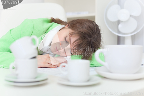 Image of Woman has got tired and sleeps on table among coffee cups