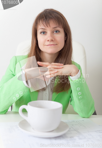 Image of Young woman sits at table with big cup of coffee