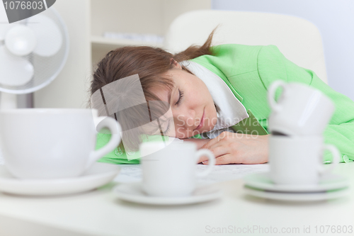 Image of Beautiful woman sleeps on workplace with coffee cups