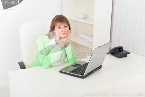 Image of Sad girl sits at white table in office