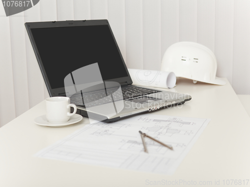 Image of Laptop, drawings, helmet and compasses on table