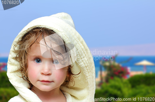 Image of cute girl in bathrobe on beach