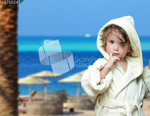 Image of cute girl in bathrobe on beach