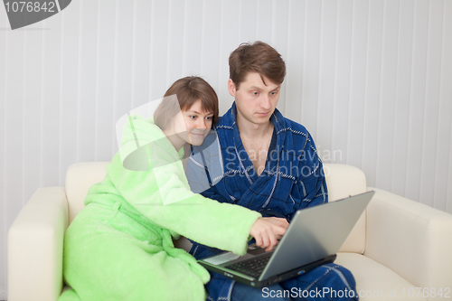 Image of Man and woman sit on sofa with laptop