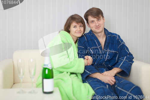 Image of Young pair on a sofa with sparkling wine