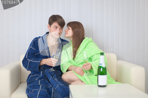 Image of Guy and girl drink champagne wine on a sofa