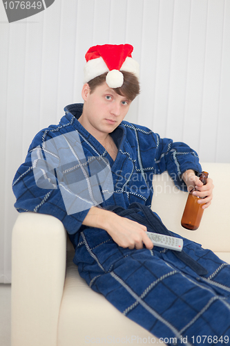 Image of Man in Christmas cap with remote control and beer