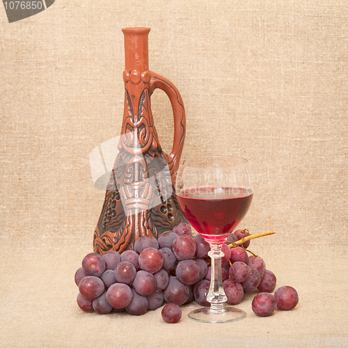 Image of Still-life with clay bottle, grapes and glass on canvas backgrou