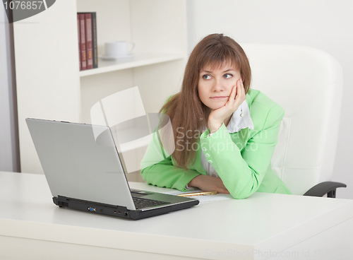 Image of Young businesswoman sits on workplace