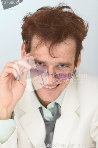 Image of Cheerful tousled guy looks over eyeglasses