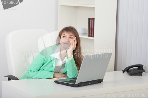 Image of Young woman dreams sitting at a table with laptop