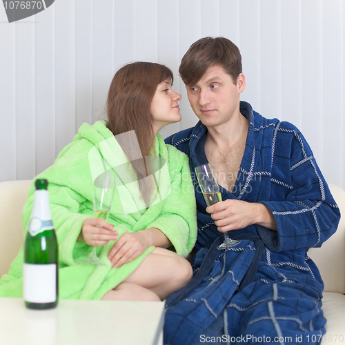 Image of Guy and girl drink champagne wine on a sofa