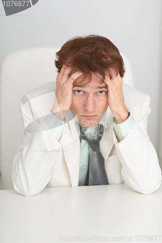 Image of Sad young businessman sits at a table