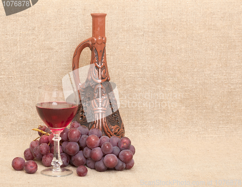Image of Clay bottle, grapes and glass on canvas background