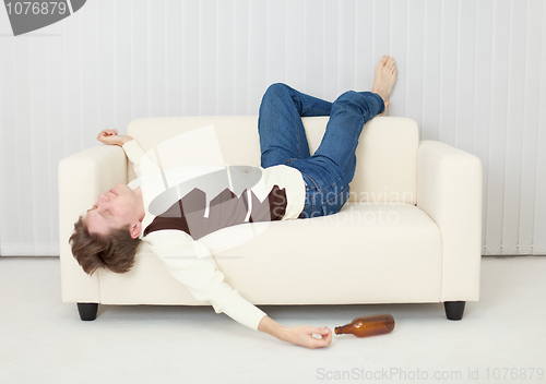 Image of Drunkard sleeps on sofa in an amusing pose