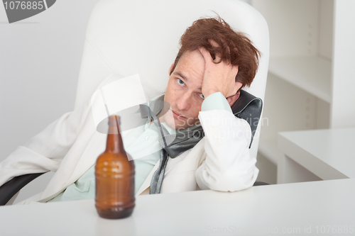 Image of Young drunken man at office with a beer bottle