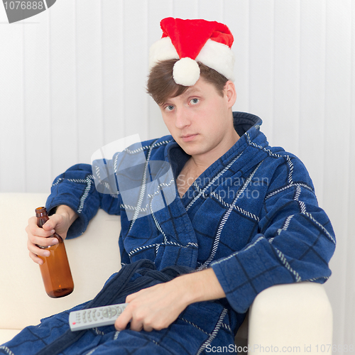 Image of Man in Christmas cap with remote control and beer