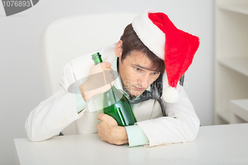 Image of Young guy in Christmas cap with a bottle